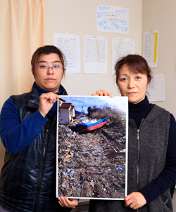 震災直後の大船渡市内の写真を手にする臼井亜希子さん（左）と今井久美子さん