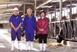 藤田与一さん（中央）をはさんで、後継者の宗隆さん（左）と妻の恵子さん。宗隆さんは「酪農は努力した分だけ結果がついてくる仕事」と未来に目を向ける